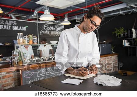 Chef in restaurant writing in notepad View Large Photo Image Stock Image - Chef in restaurant writing in notepad. Fotosearch