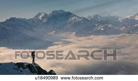 Climber on a peak emerging from fog in the Alps, Bettmeralp, Valais, Switzerland View Large Photo Image Stock Photo - Climber on a peak emerging from fog in the Alps, Bettmeralp, Valais, Switzerland. Fotosearch