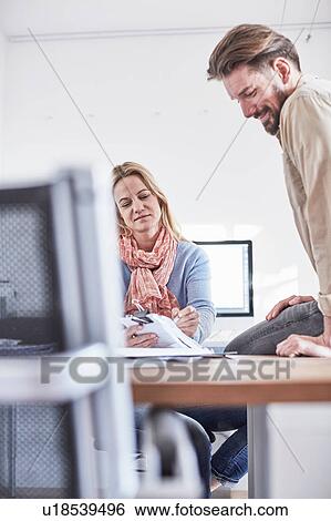 Colleagues in office looking at paperwork View Large Photo Image Stock Photograph - Colleagues in office looking at paperwork. Fotosearch