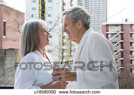 Stock Image - Couple chatting, having coffee on balcony. Fotosearch