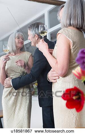 Stock Photo - Couple dressed up and having drink in front of mirror. Fotosearch