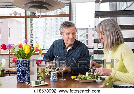 Stock Image - Couple enjoying meal at dining table. Fotosearch