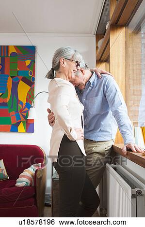 Couple hugging beside window View Large Photo Image Stock Photograph - Couple hugging beside window. Fotosearch