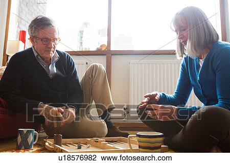 Stock Image - Couple playing backgammon on floor. Fotosearch