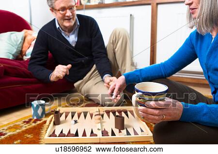 Couple playing backgammon on floor View Large Photo Image Stock Image - Couple playing backgammon on floor. Fotosearch