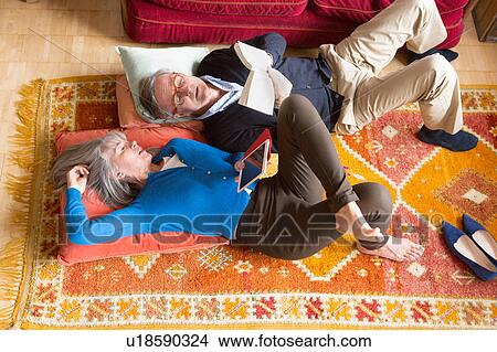 Picture - Couple reading book on floor. Fotosearch