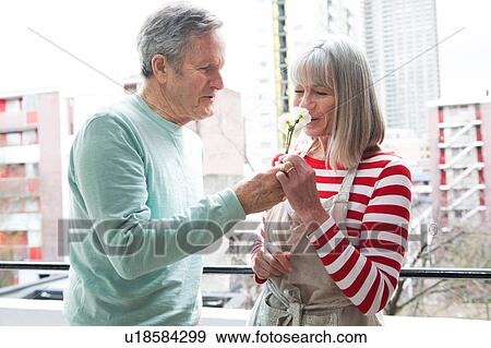 Stock Photo - Couple smelling flower on balcony. Fotosearch