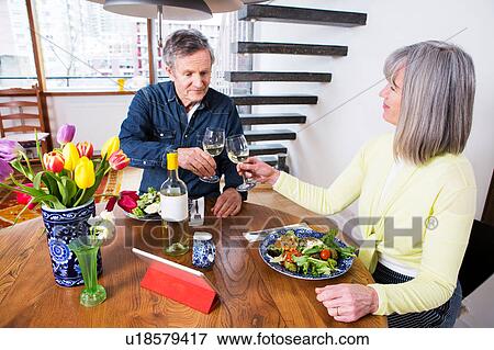 Stock Photo - Couple toasting at dining table. Fotosearch