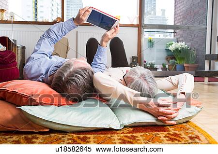 Couple using digital tablet on floor View Large Photo Image Stock Photography - Couple using digital tablet on floor. Fotosearch