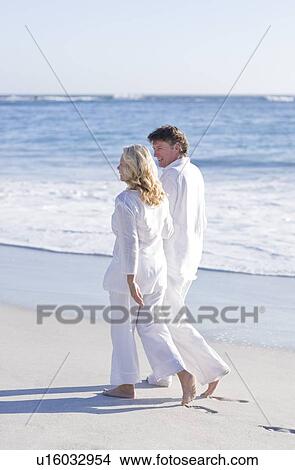 Couple walking along a beach View Large Photo Image Picture - Couple walking along a beach. Fotosearch