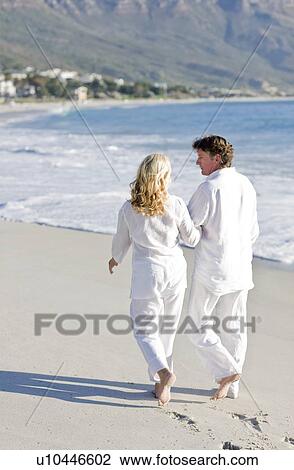 Couple walking along a beach View Large Photo Image Stock Image - Couple walking along a beach. Fotosearch