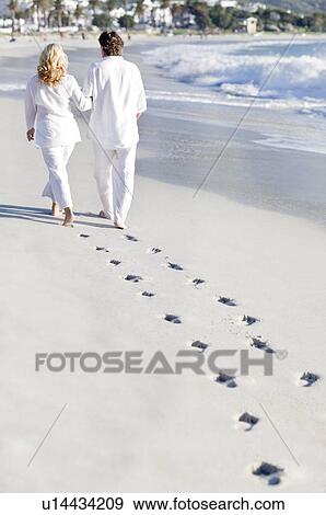 Stock Photo - Couple walking along a beach. Fotosearch