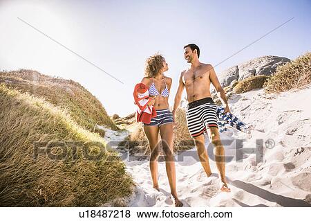 Couple walking on sand dune carrying beach umbrella and towel, Cape Town, South Africa View Large Photo Image Stock Photo - Couple walking on sand dune carrying beach umbrella and towel, Cape Town, South Africa. Fotosearch