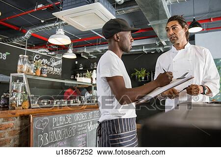 Employee in restaurant talking with chef, making notes on clipboard View Large Photo Image Stock Image - Employee in restaurant talking with chef, making notes on clipboard. Fotosearch