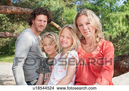 Picture - Family sitting together looking at camera smiling. Fotosearch