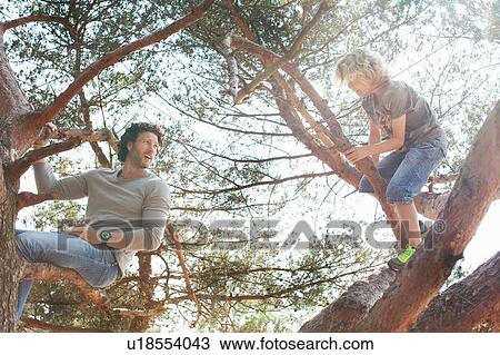 Stock Image - Father and son climbing tree. Fotosearch