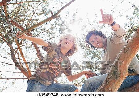 Stock Photo - Father and son climbing tree. Fotosearch