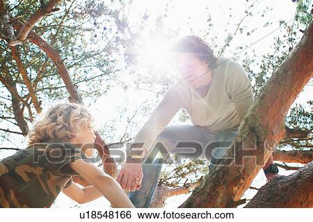 Stock Photograph - Father and son climbing tree. Fotosearch