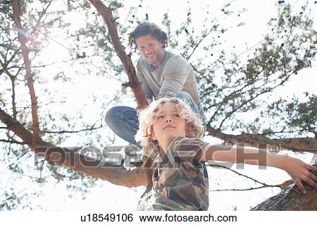 Stock Photograph - Father and son climbing tree. Fotosearch