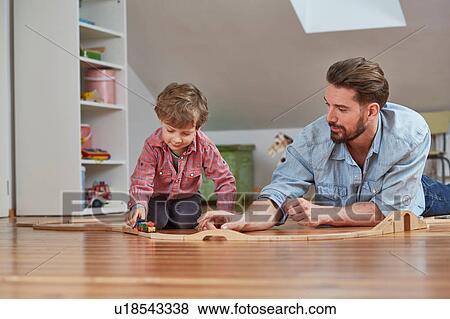 Stock Photo - Father and son playing with wooden toy train set. Fotosearch