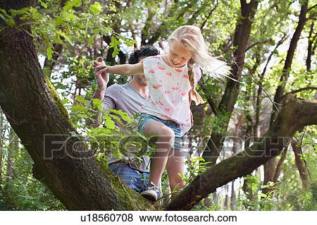 Stock Photo - Father helping daughter to climb tree. Fotosearch