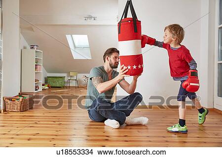 Picture - Father holding punchbag for son. Fotosearch