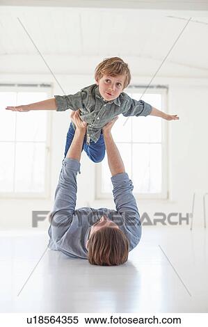 Father lying on floor holding up son View Large Photo Image Stock Photography - Father lying on floor holding up son. Fotosearch