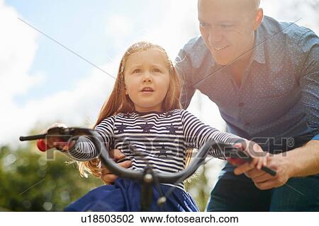 Father teaching daughter to ride bicycle View Large Photo Image Stock Image - Father teaching daughter to ride bicycle. Fotosearch