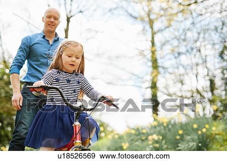 Father teaching daughter to ride bicycle View Large Photo Image Stock Photo - Father teaching daughter to ride bicycle. Fotosearch