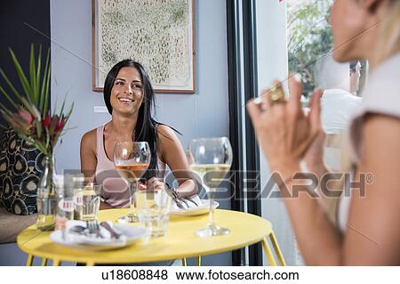 Stock Photo - Friends chatting during lunch in restaurant. Fotosearch