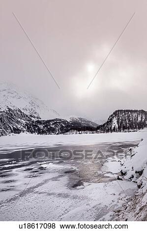 Stock Photo - Frozen lake and snow covered mountains, Engadin, Switzerland. Fotosearch