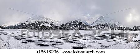 Stock Photograph - Frozen lake and snow covered mountains, Engadin, Switzerland. Fotosearch