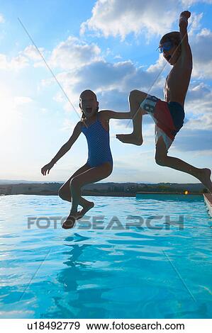 Stock Photo - Girl and brother jumping into swimming pool, Buonconvento, Tuscany, Italy. Fotosearch