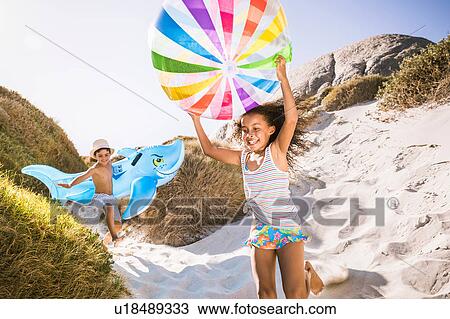 Girl and brother running down sand dune carrying shark inflatable and beachball, Cape Town, South Africa View Large Photo Image Stock Image - Girl and brother running down sand dune carrying shark inflatable and beachball, Cape Town, South Africa. Fotosearch