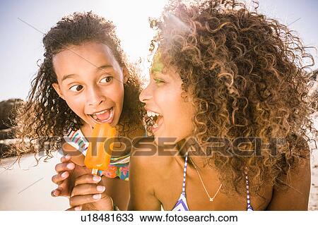 Girl and mother sharing ice lolly on beach, Cape Town, South Africa View Large Photo Image Stock Image - Girl and mother sharing ice lolly on beach, Cape Town, South Africa. Fotosearch