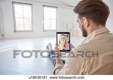 Girlfriend on digital tablet video call blowing a kiss to young man sitting on floor View Large Photo Image Stock Image - Girlfriend on digital tablet video call blowing a kiss to young man sitting on floor. Fotosearch