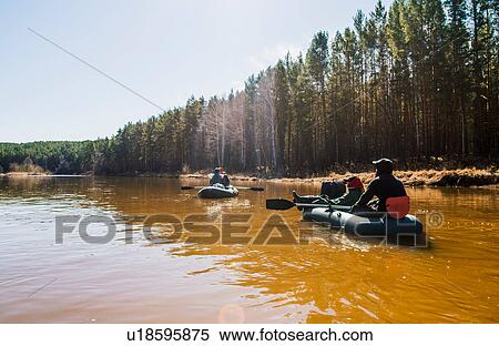 Stock Photography - Group of friends rowing dinghies on river. Fotosearch