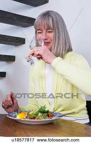 Happy woman drinking wine at dining table View Large Photo Image Stock Photo - Happy woman drinking wine at dining table. Fotosearch