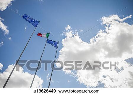 Stock Photo - Low angle view of flags flapping in wind on flagpole, Italy. Fotosearch