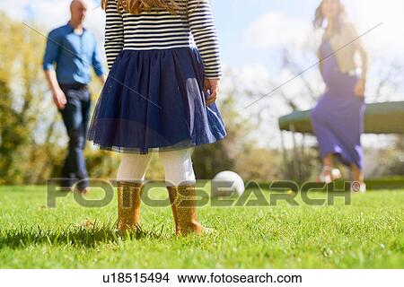 Picture - Low section of girl in garden with family playing with football. Fotosearch