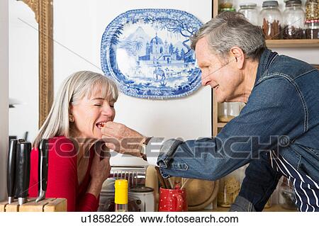 Man feeding wife in kitchen View Large Photo Image Stock Photograph - Man feeding wife in kitchen. Fotosearch