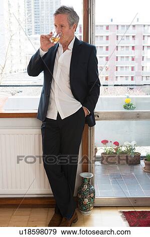 Man in smart clothes drinking beside window View Large Photo Image Stock Photo - Man in smart clothes drinking beside window. Fotosearch