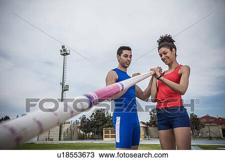 Man instructing young female pole vaulter at sport facility View Large Photo Image Stock Image - Man instructing young female pole vaulter at sport facility. Fotosearch