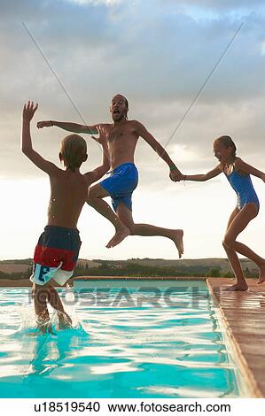 Stock Image - Man jumping into swimming pool with daughter and son, Buonconvento, Tuscany, Italy. Fotosearch