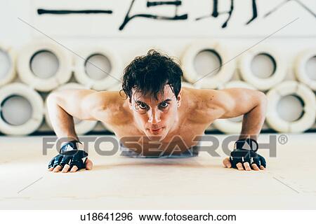 Stock Photograph - Man looking at camera doing press ups. Fotosearch