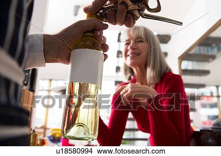 Man opening bottle of wine in kitchen View Large Photo Image Picture - Man opening bottle of wine in kitchen. Fotosearch