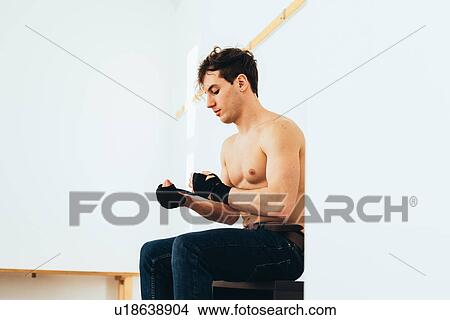 Picture - Man sitting in changing room wrapping hands. Fotosearch