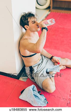 Man sitting leaning against column wearing heart rate monitor on chest, drinking water from bottle View Large Photo Image Stock Photography - Man sitting leaning against column wearing heart rate monitor on chest, drinking water from bottle. Fotosearch