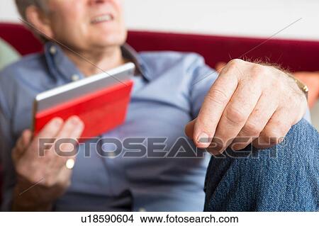 Picture - Man using digital tablet at home. Fotosearch