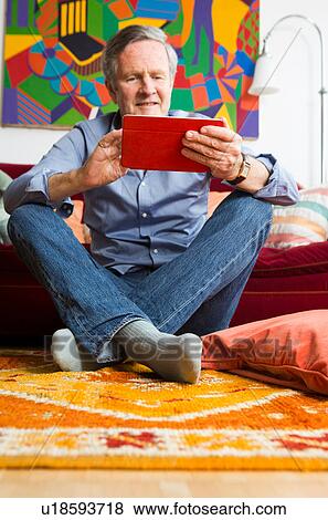 Stock Photo - Man using digital tablet at home. Fotosearch